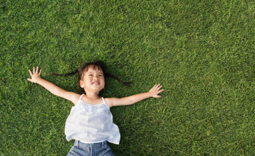 Asian little girl smile and lay on grass