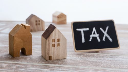 Property tax concept with model of houses with tax sign on wooden table