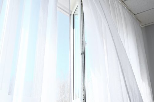 Open window with light curtains in room